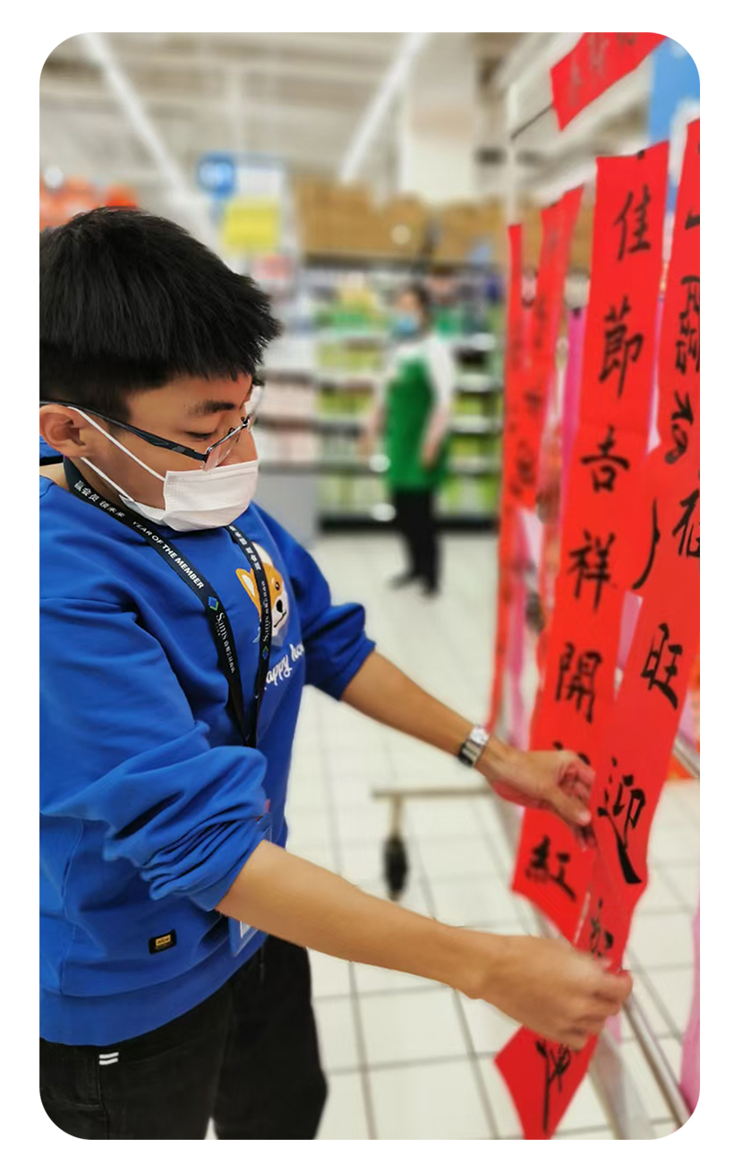 Associate Hongtao Li hangs his Spring Festival couplets, which are black calligraphy on red paper, in his store.